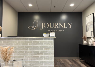 Journey Psychology reception area with front desk, logo wall, and modern, welcoming interior design.
